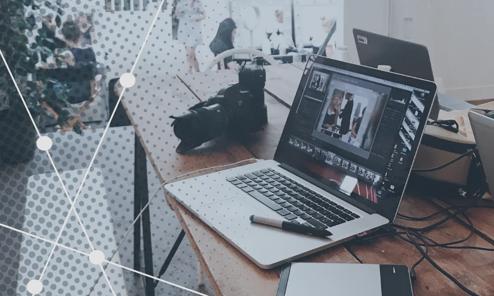 Laptop on desk with camera, pen, and notebook, representing marketing, SEO, digital marketing, social media, and public relations work in a modern office environment.